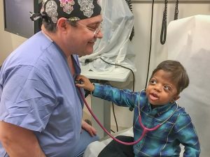 Image of Dr. David Staffenberg with a young patient holding a stethoscope to Dr. Staffenberg's heart.