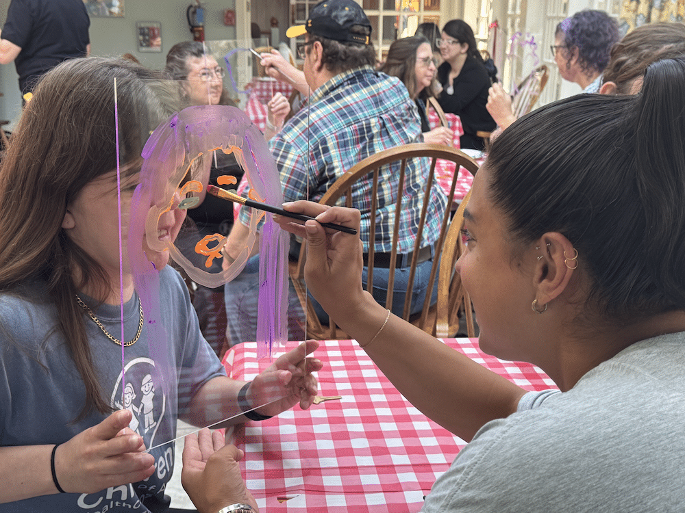 retreat_6 participant painting another participant's face on glass