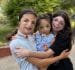 2 girls embracing a young child, all smiling